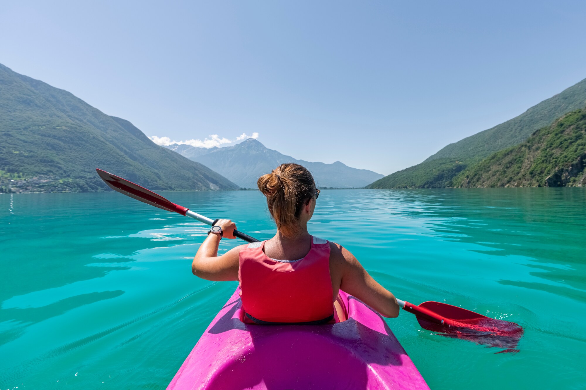 Eine Frau paddelt zwischen Bergen übers Wasser