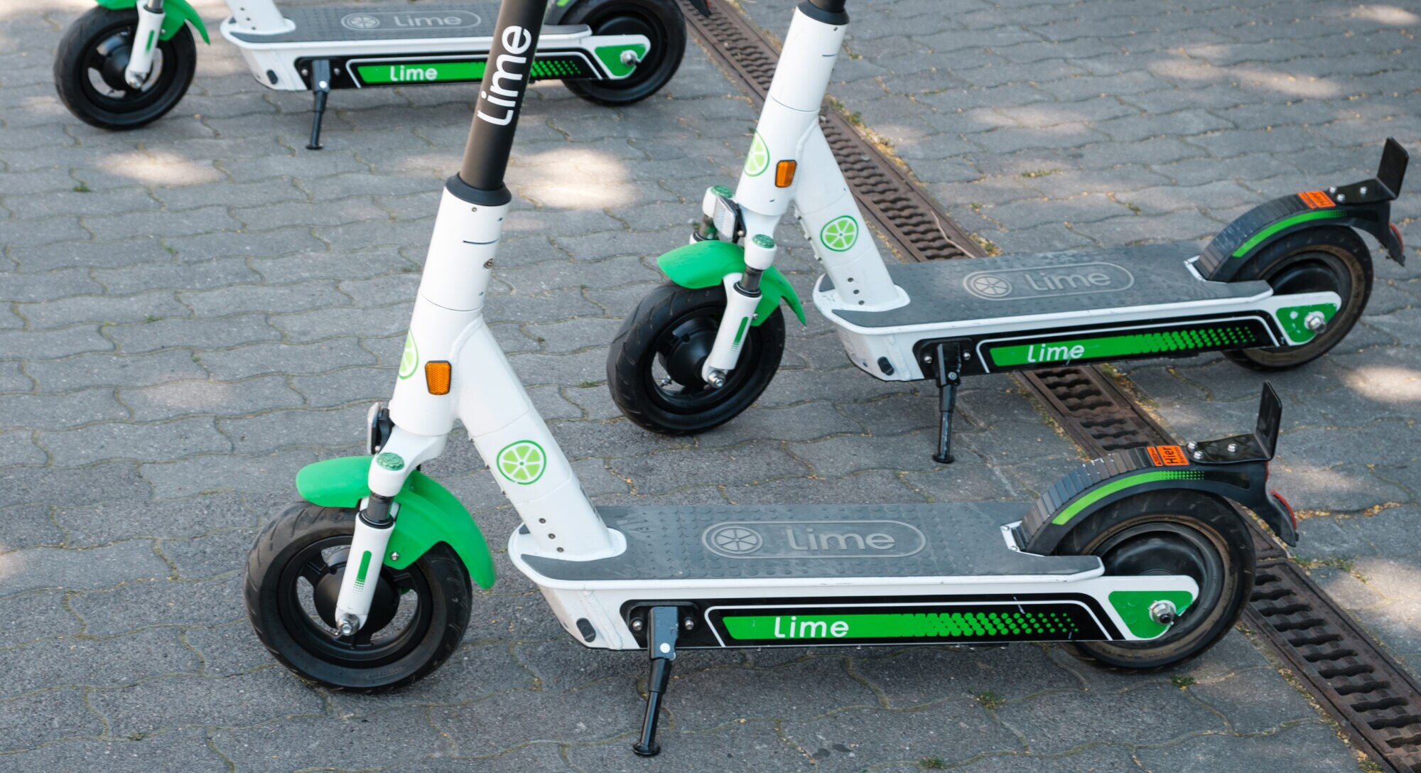 Vier grüne E-Scooter stehen geparkt auf der Straße