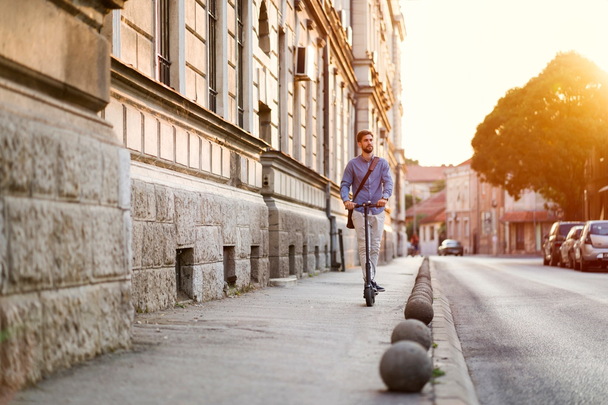 Ein junger Mann fährt mit einem E-Scooter auf einem Gehweg Ein junger Mann fährt mit einem E-Scooter auf einem Gehweg