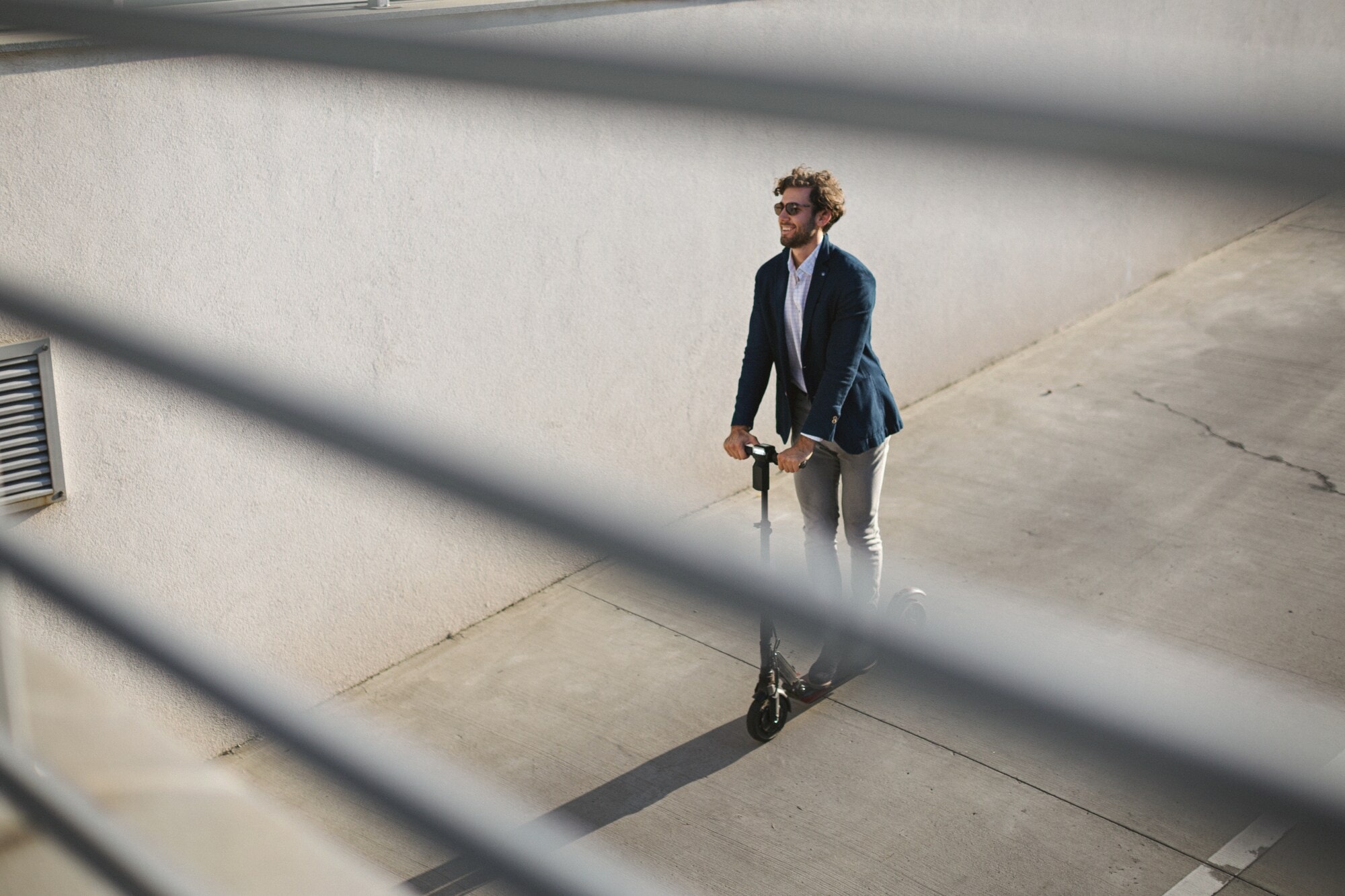 Ein elegant gekleideter, junger Mann auf einem E-Scooter Ein elegant gekleideter, junger Mann auf einem E-Scooter