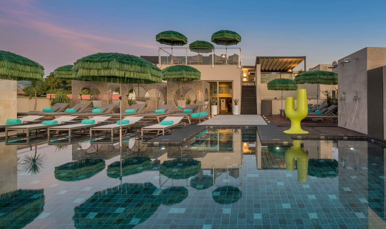 Mehrere Strandliegen stehen direkt an einem Pool und unter grünen Sonnenschirmen. Mehrere Strandliegen stehen direkt an einem Pool und unter grünen Sonnenschirmen.