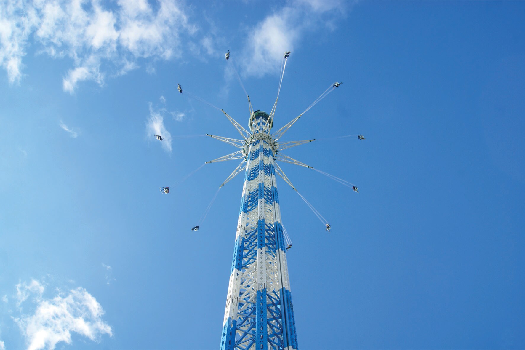 Ein blau weißes Kettenkarussell vor blauem Himmel
