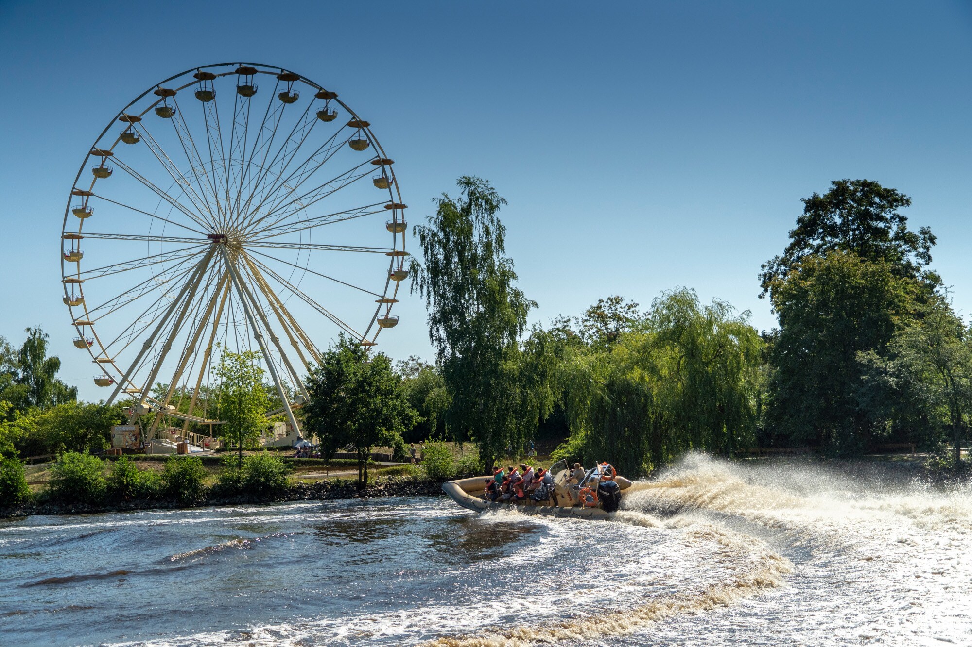 Serengeti Park, Splash Safari Ein Motorboot auf einem See, im Hintergrund ein Riesenrad