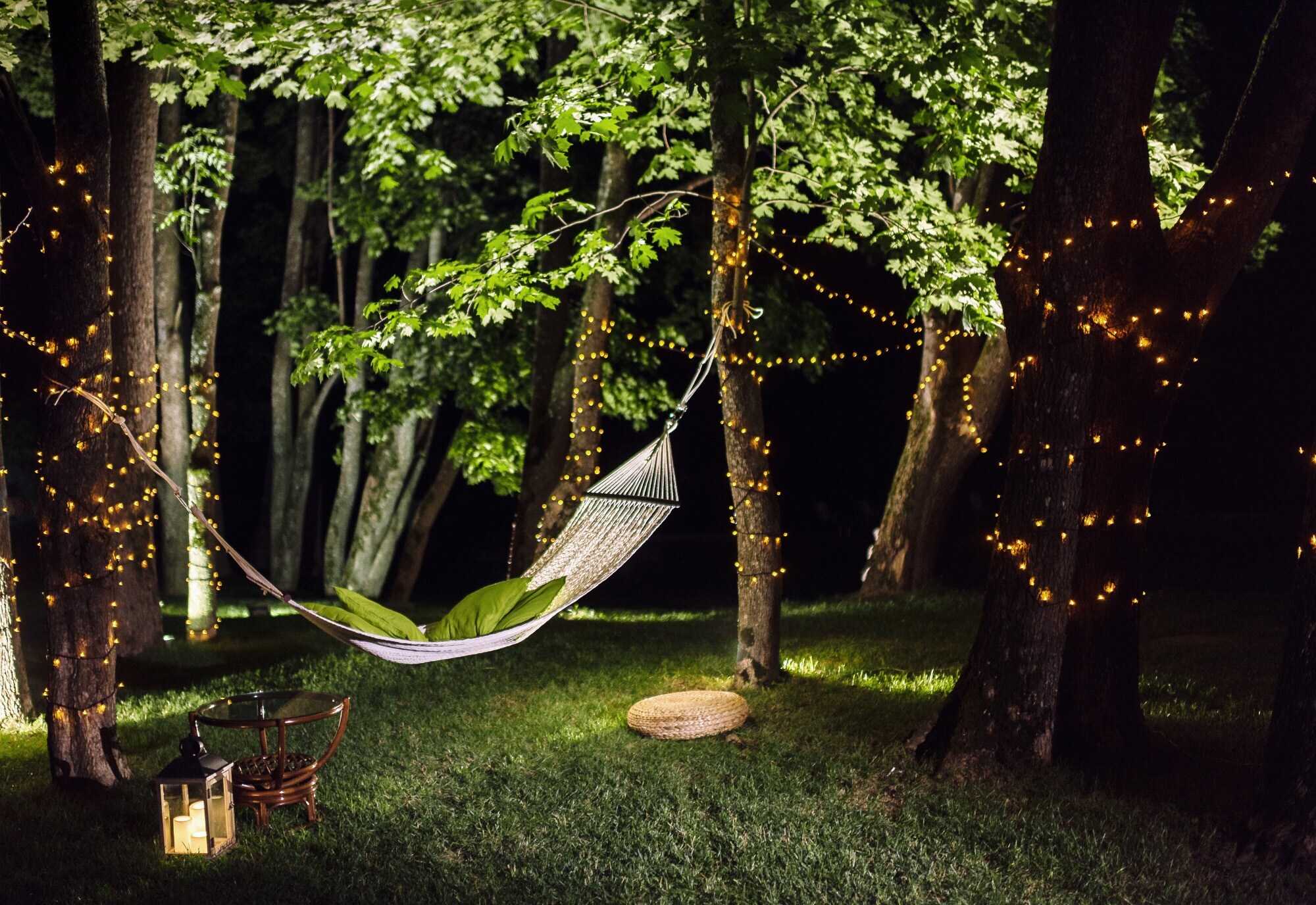 Eine Hängematte in einem Garten mit beleuchteten Bäumen bei Nacht