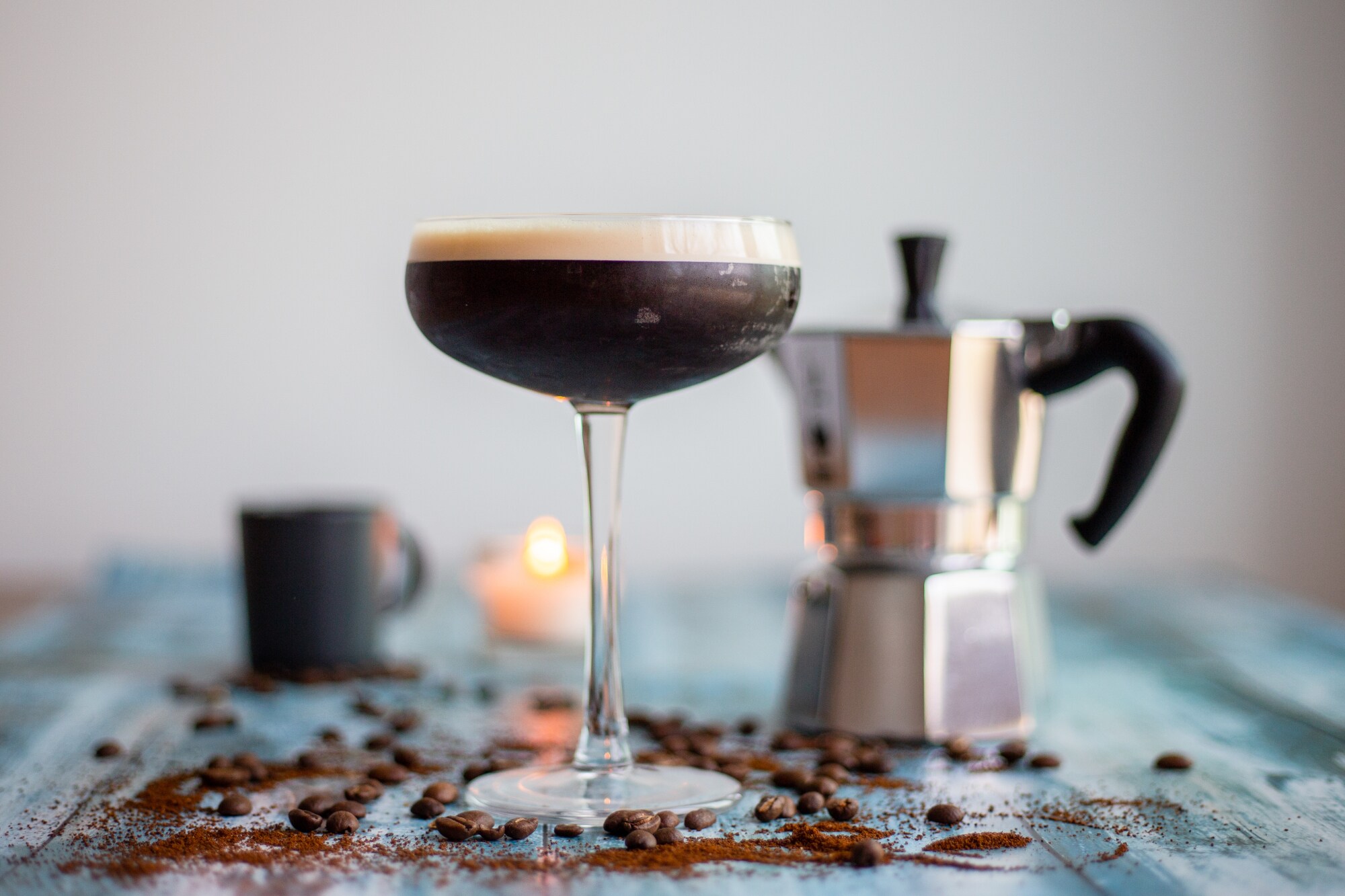 Ein Cocktail mit Kaffee zubereitet in einem Martiniglas, daneben eine Kaffeekanne