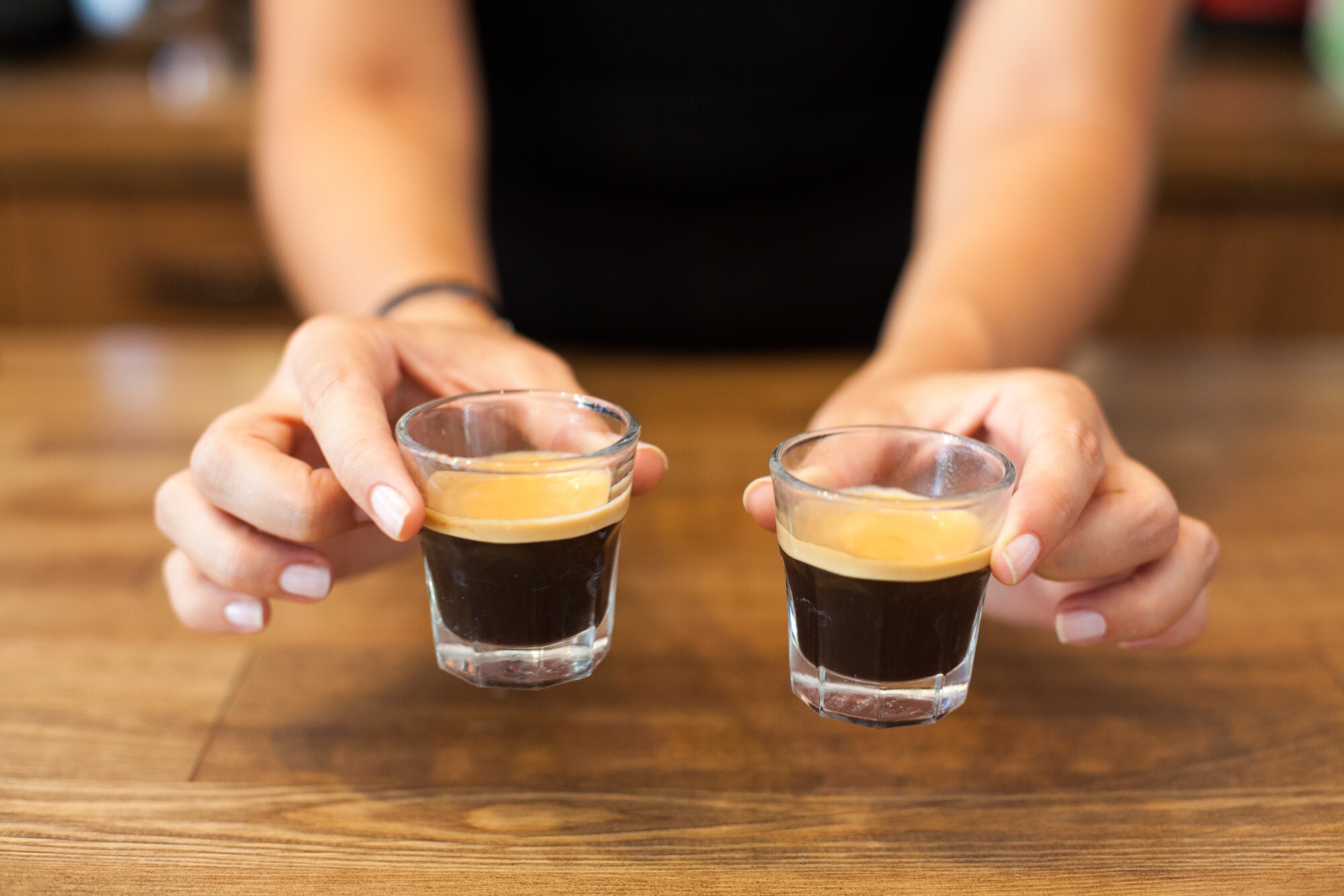 Eine Frau hält zwei Gläser mit Espresso in den Händen