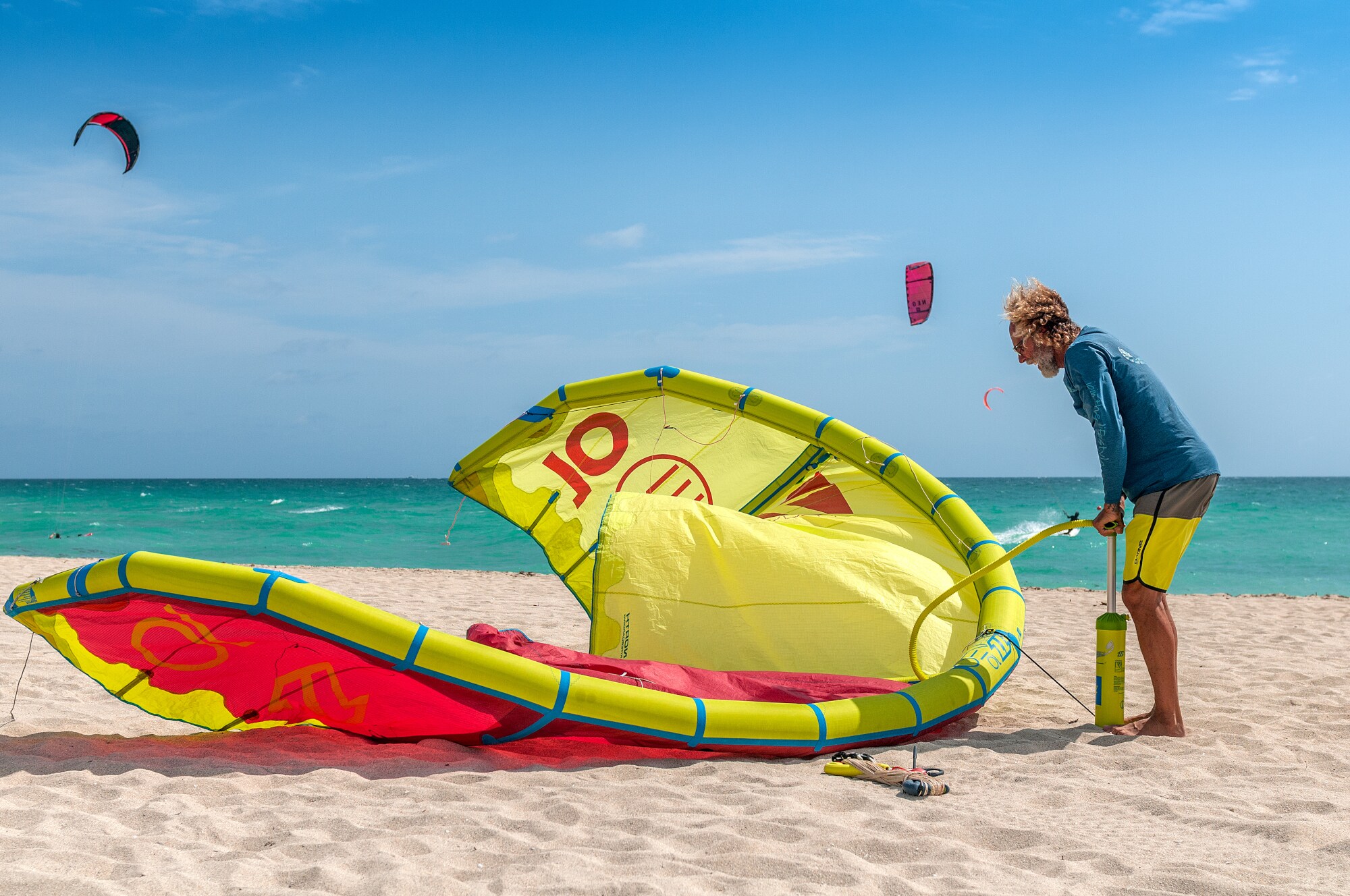 Kitesurfer pumpt am Strand sein Kite mit einer Pumpe auf Kitesurfer pumpt am Strand sein Kite mit einer Pumpe auf
