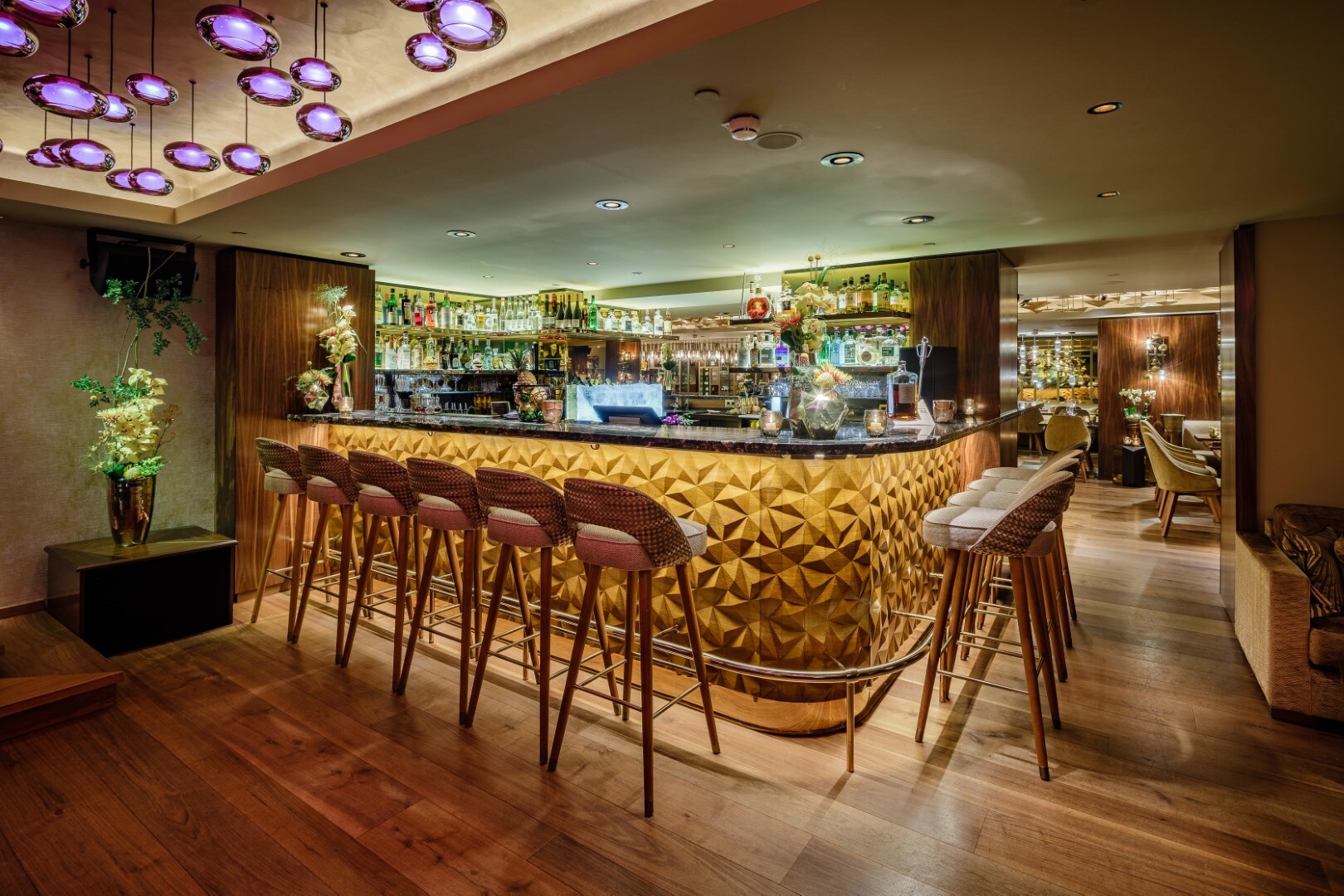 Innenraum einer modern eingerichteten Bar mit gepolsterten Barhockern vor einem Tresen Innenraum einer modern eingerichteten Bar mit gepolsterten Barhockern vor einem Tresen