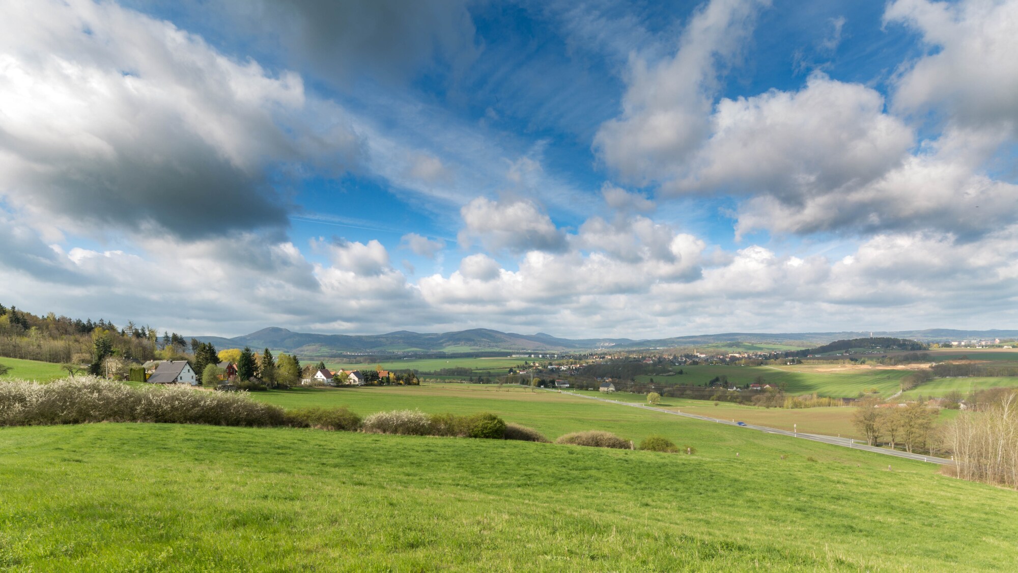 Blick auf eine sommerliche Landschaft mit Wiesen und Bergen