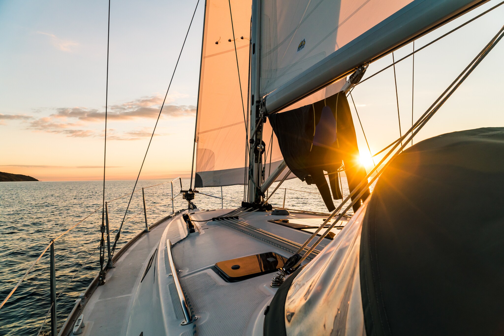 Segelboot, das in den Sonnenuntergang schippert Segelboot, das in den Sonnenuntergang schippert