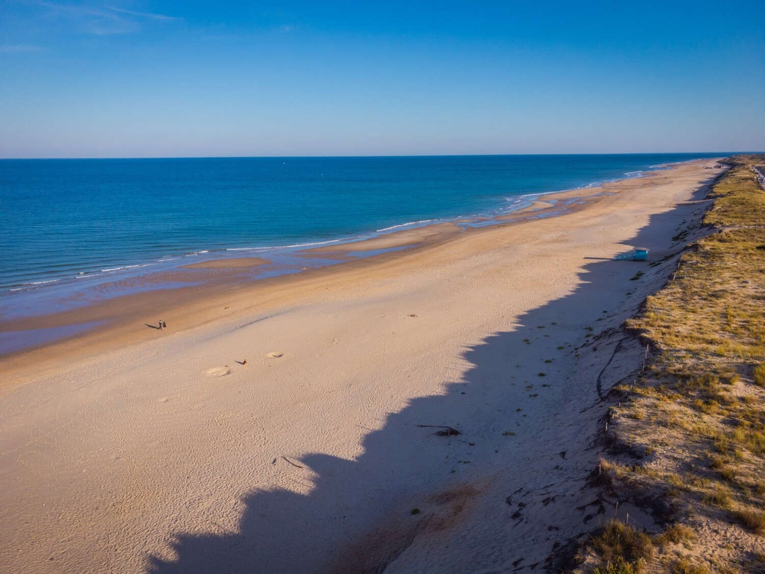 Ein langer Strand am Meer, dahinter Dünen Ein langer Strand am Meer, dahinter Dünen