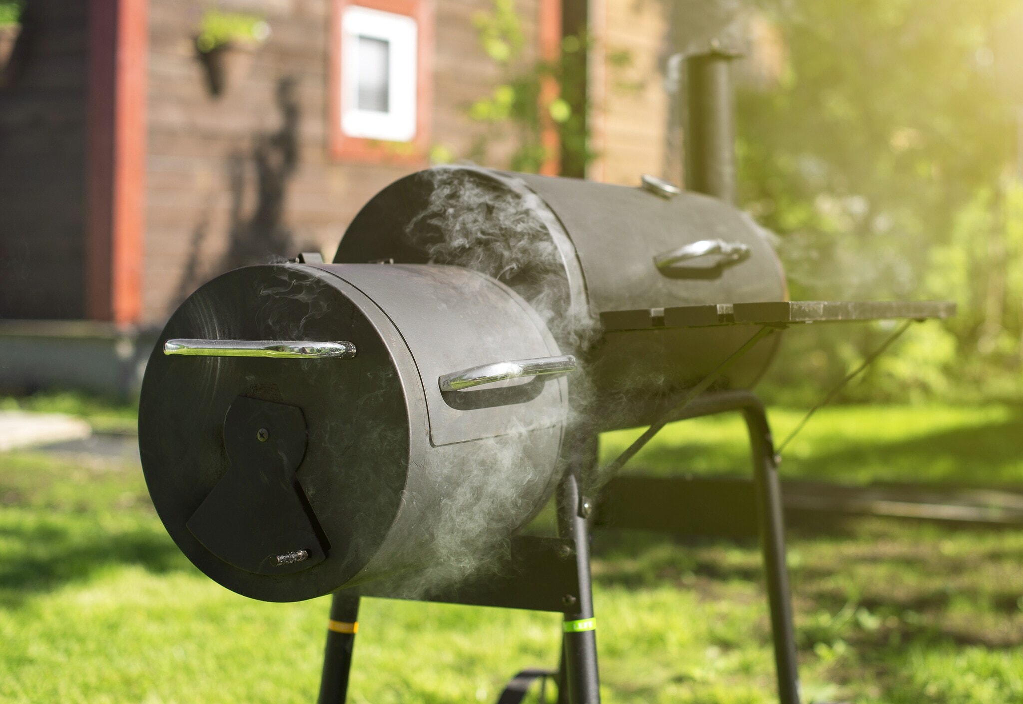 Ein qualmender Holzkohlegrill, in dem geräuchert wird Ein qualmender Holzkohlegrill, in dem geräuchert wird