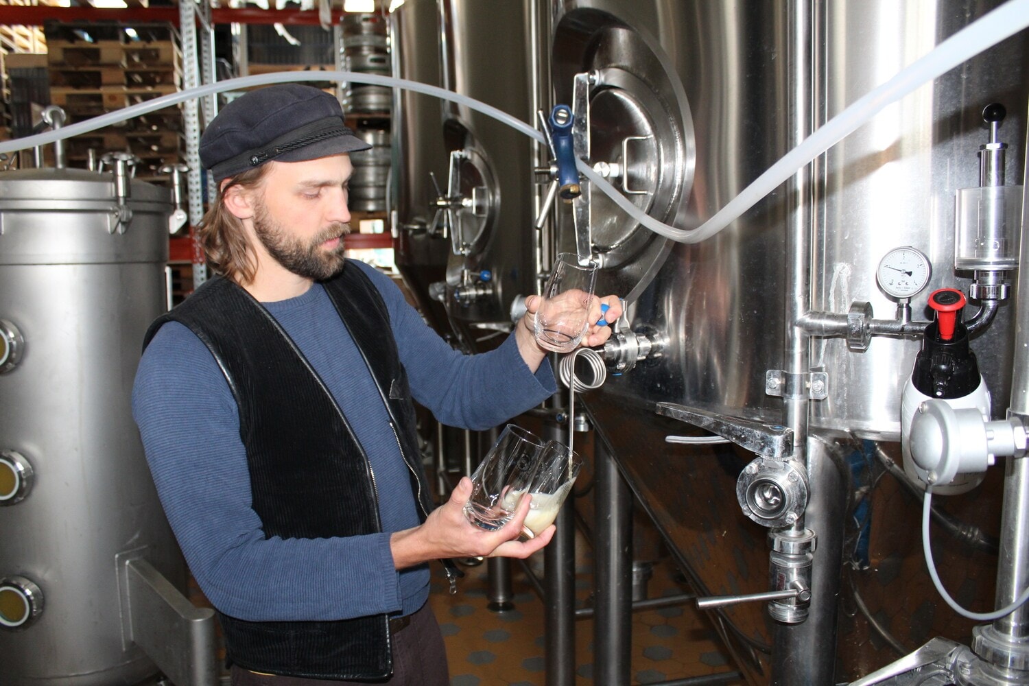 Ein Mann zapft Bier in einer Brauerei Ein Mann zapft Bier in einer Brauerei