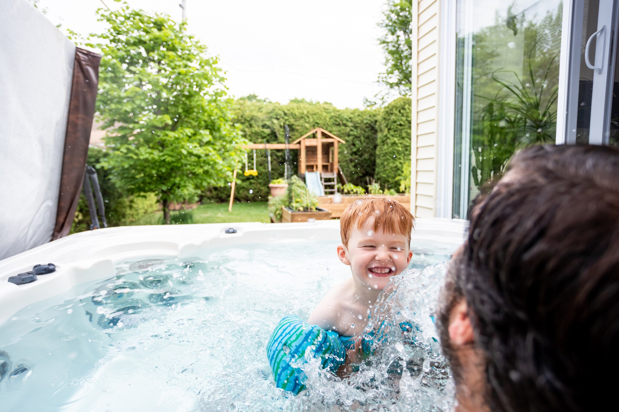 Ein kleiner rothaariger Junge hat mit seinem Vater Spaß im Whirlpool im Garten