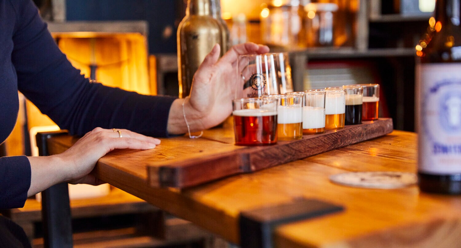 Verschiedene Biersorten auf einem Holzbrett bei einer Verkostung