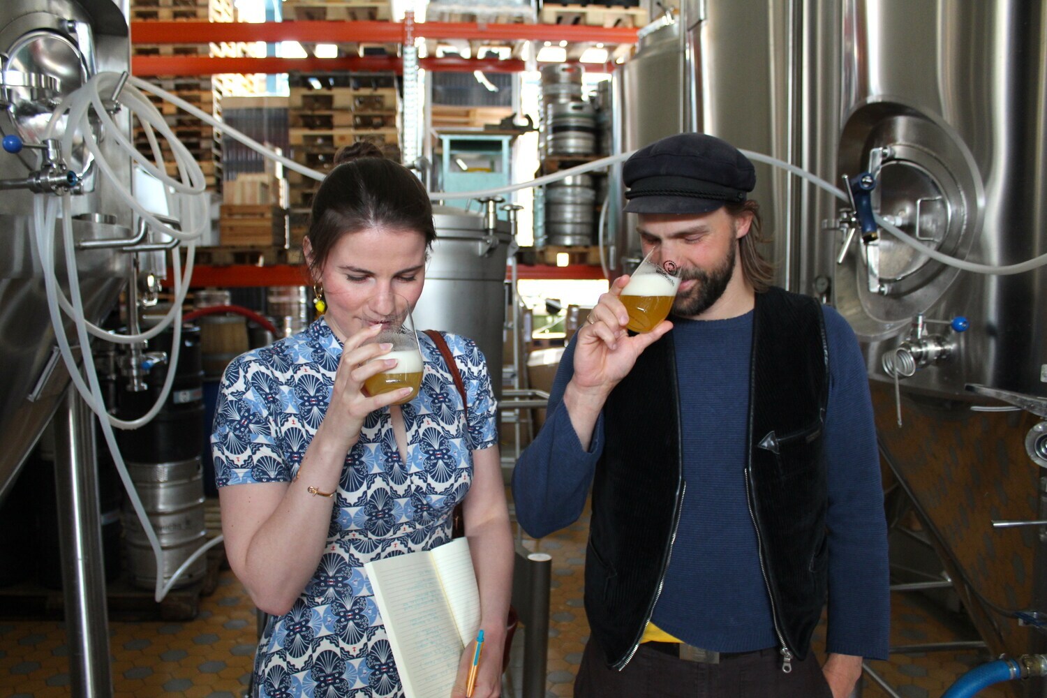 Zwei Personen riechen an gefüllten Biergläsern in einer Brauerei