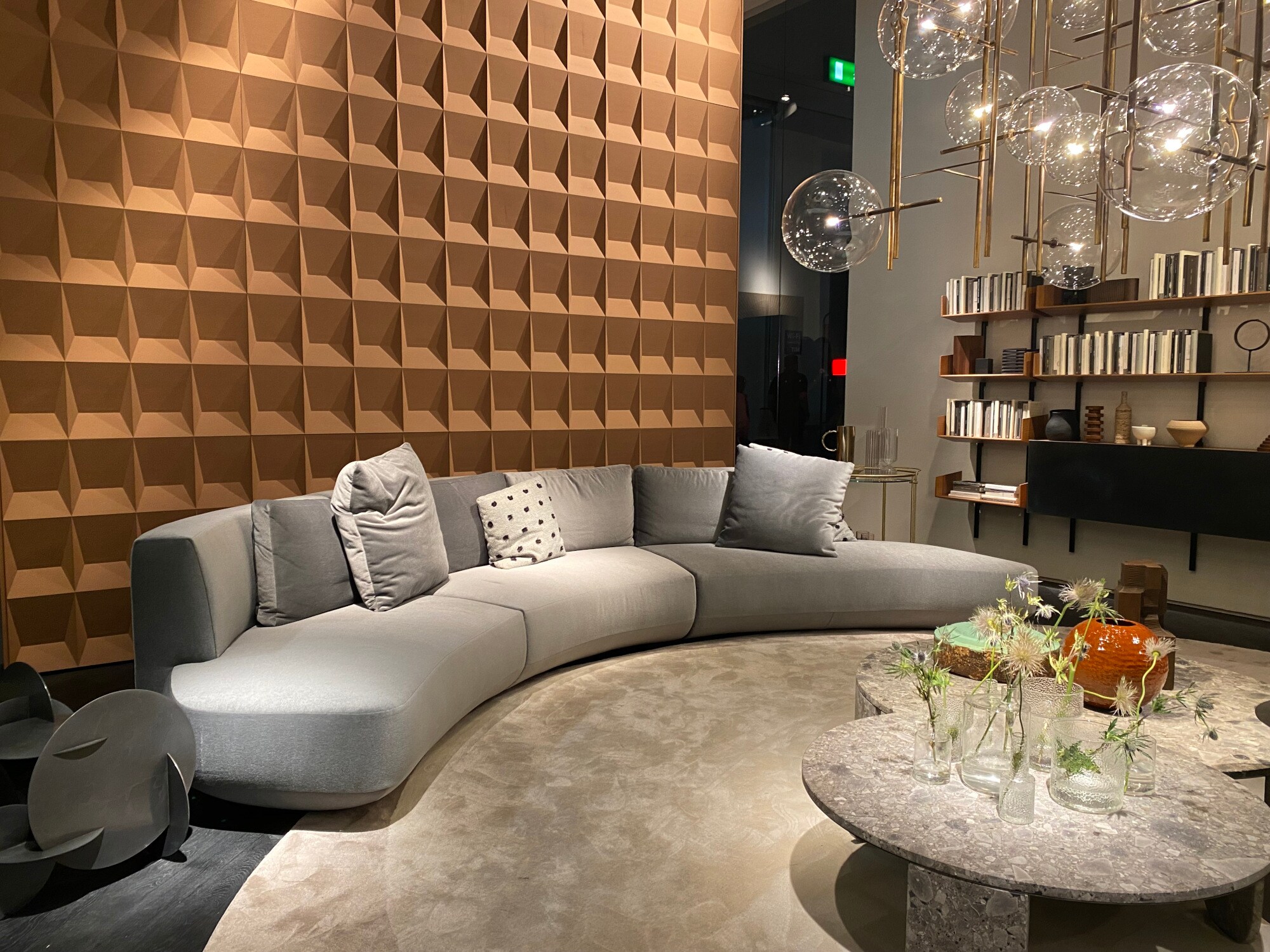 Ein graues leicht gebogenes Sofa vor einer Holzwand