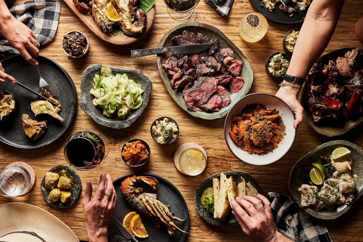 Blick auf einen Holztisch mit vielen Schalen und Tellern voller Speisen