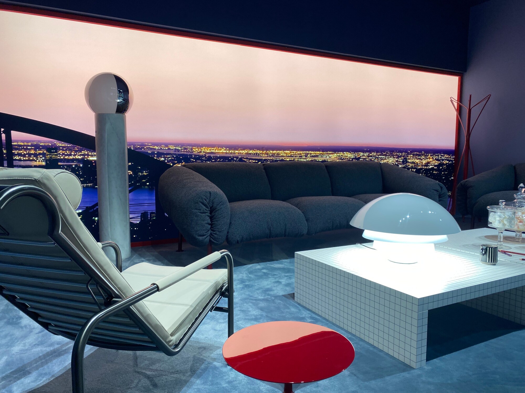 Wohnzimmerlandschaft vor einem Panoramafenster mit Blick auf eine Großstadt Wohnzimmerlandschaft vor einem Panoramafenster mit Blick auf eine Großstadt