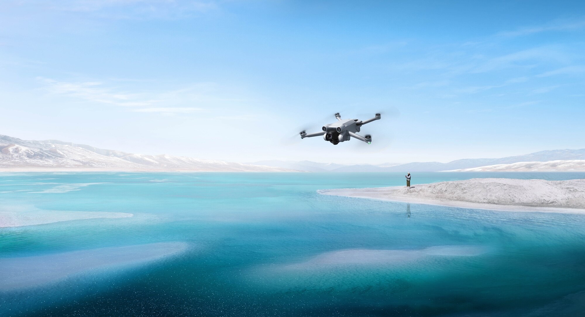 Drohne DJI Mini 3 Pro wird von einer Person in weiter Entfernung über einen kristallblauen See geflogen Drohne DJI Mini 3 Pro wird von einer Person in weiter Entfernung über einen kristallblauen See geflogen