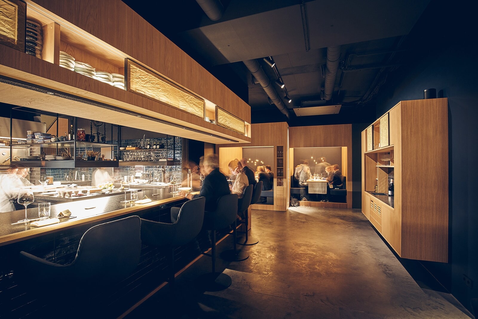 Blick in den Gastraum des Restaurants Intense mit langem Tresen und Sitznischen in einem Mix aus Industrie-Chic und warmen Hölzern. Blick in den Gastraum des Restaurants Intense mit langem Tresen und Sitznischen in einem Mix aus Industrie-Chic und warmen Hölzern.