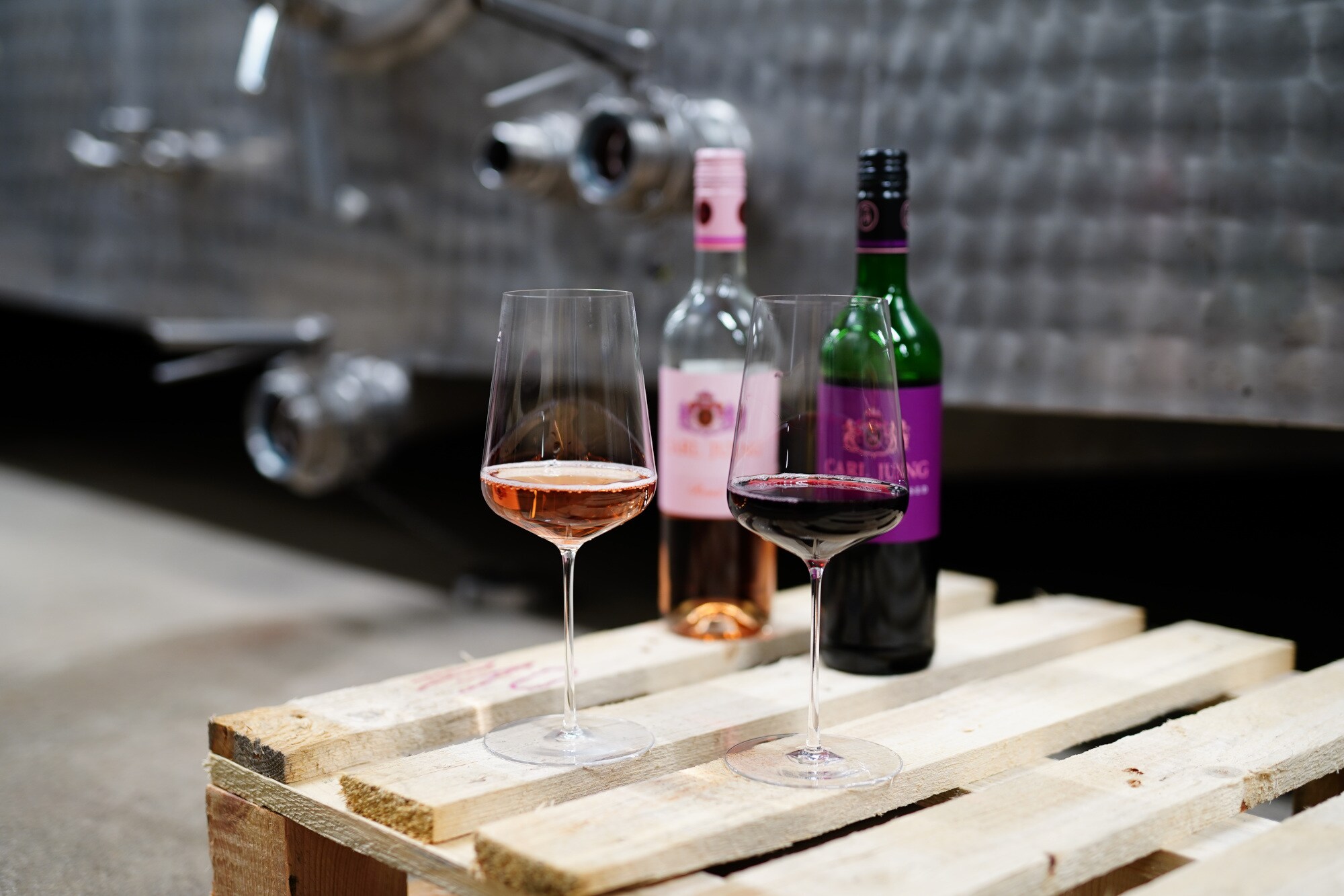 Zwei gefüllte Weingläser stehen auf einer Holzpalette Zwei gefüllte Weingläser stehen auf einer Holzpalette