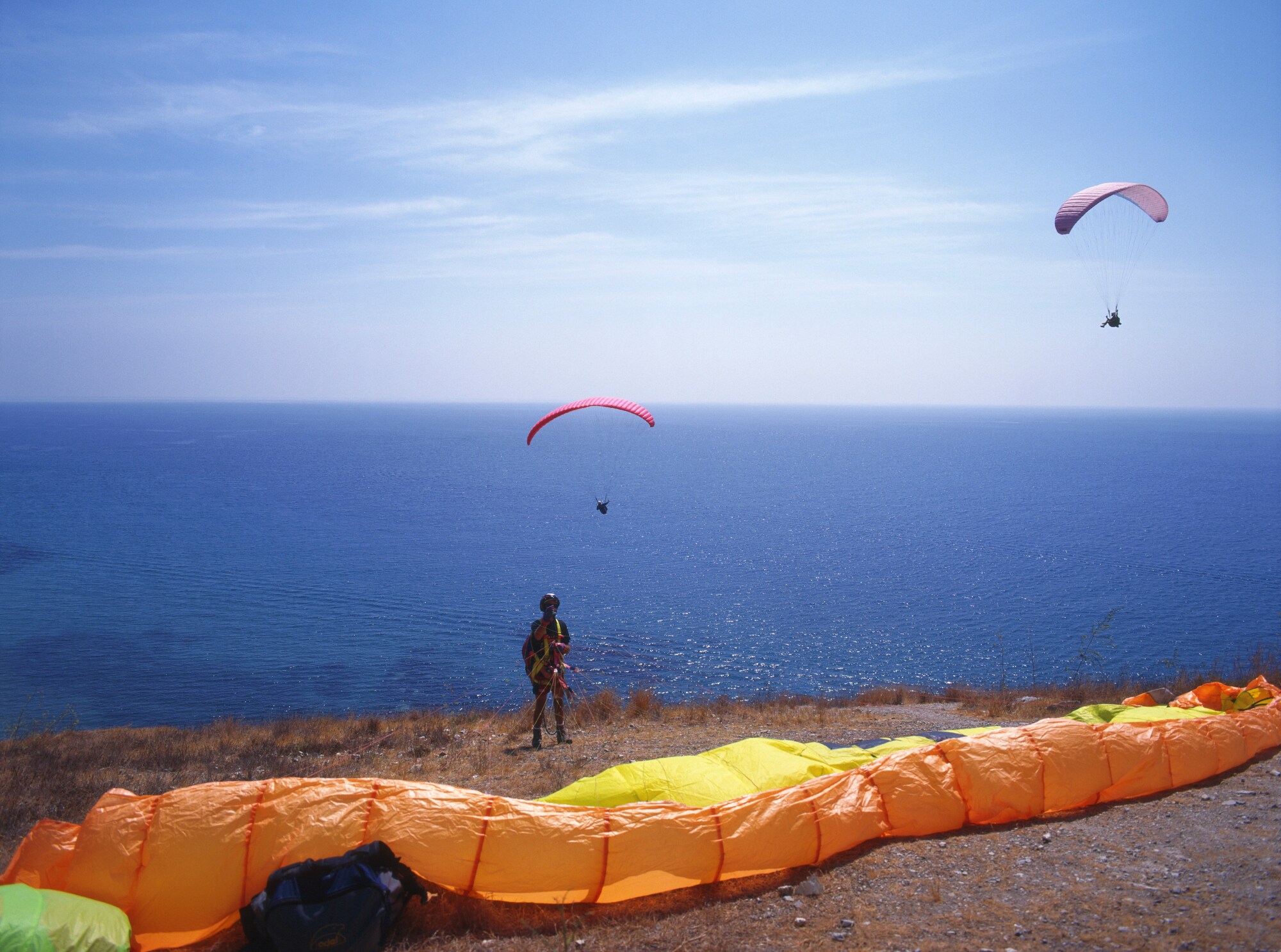 Ein Paraglider macht sich zum Absprung bereit, vor ihm das Meer