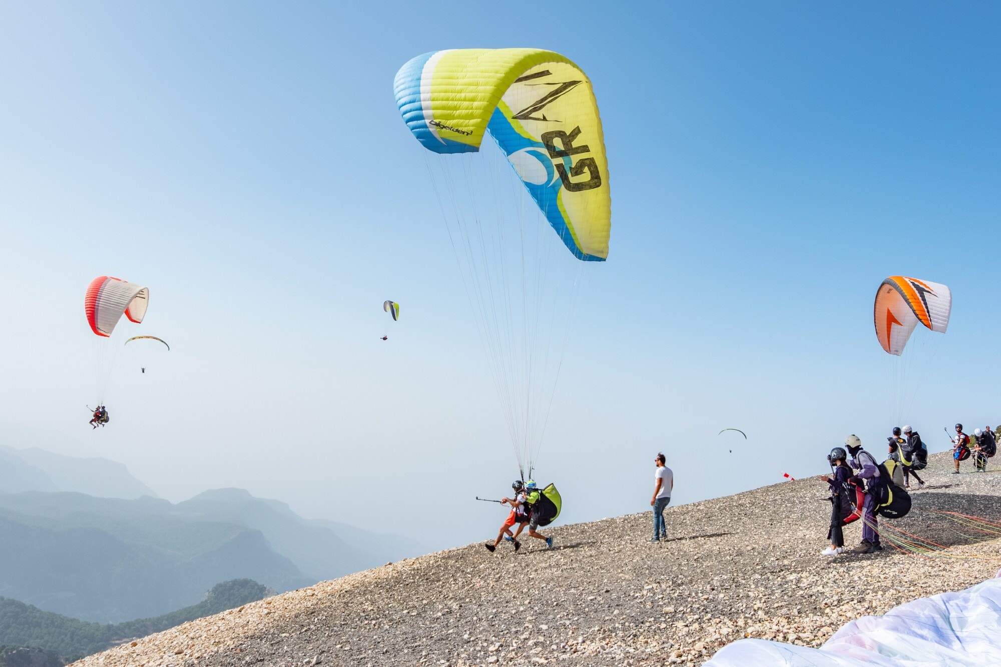 Mehrere Paraglider üben an einem Bergabhang den Absprung Mehrere Paraglider üben an einem Bergabhang den Absprung