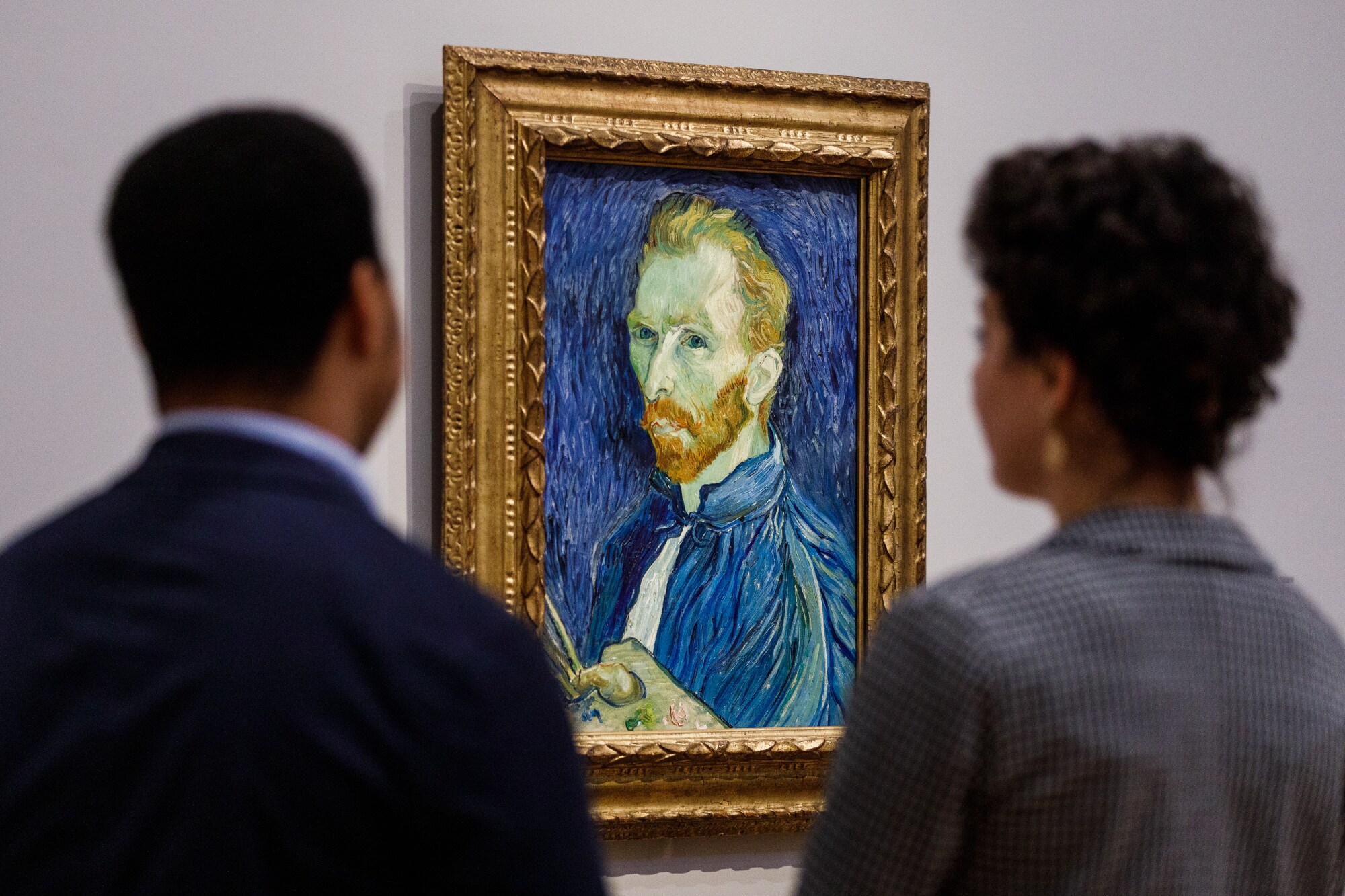 Zwei Personen betrachten ein Selbstporträt von Vincent van Gogh in einem Museum Zwei Personen betrachten ein Selbstporträt von Vincent van Gogh in einem Museum