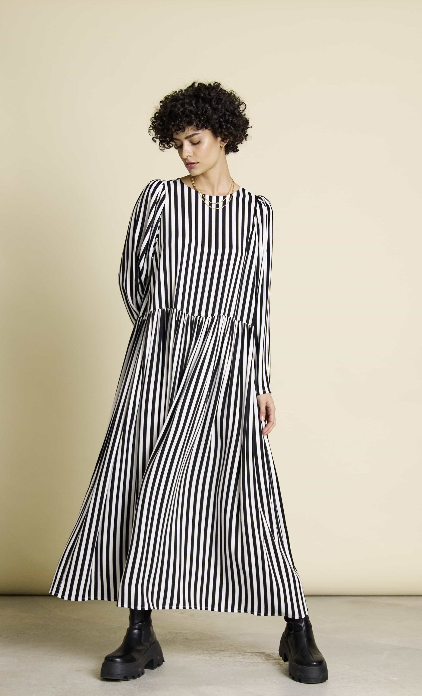 Eine Frau trägt ein weit geschnittenes, schwarz-weiß gestreiftes Maxikleid Eine Frau trägt ein weit geschnittenes, schwarz-weiß gestreiftes Maxikleid