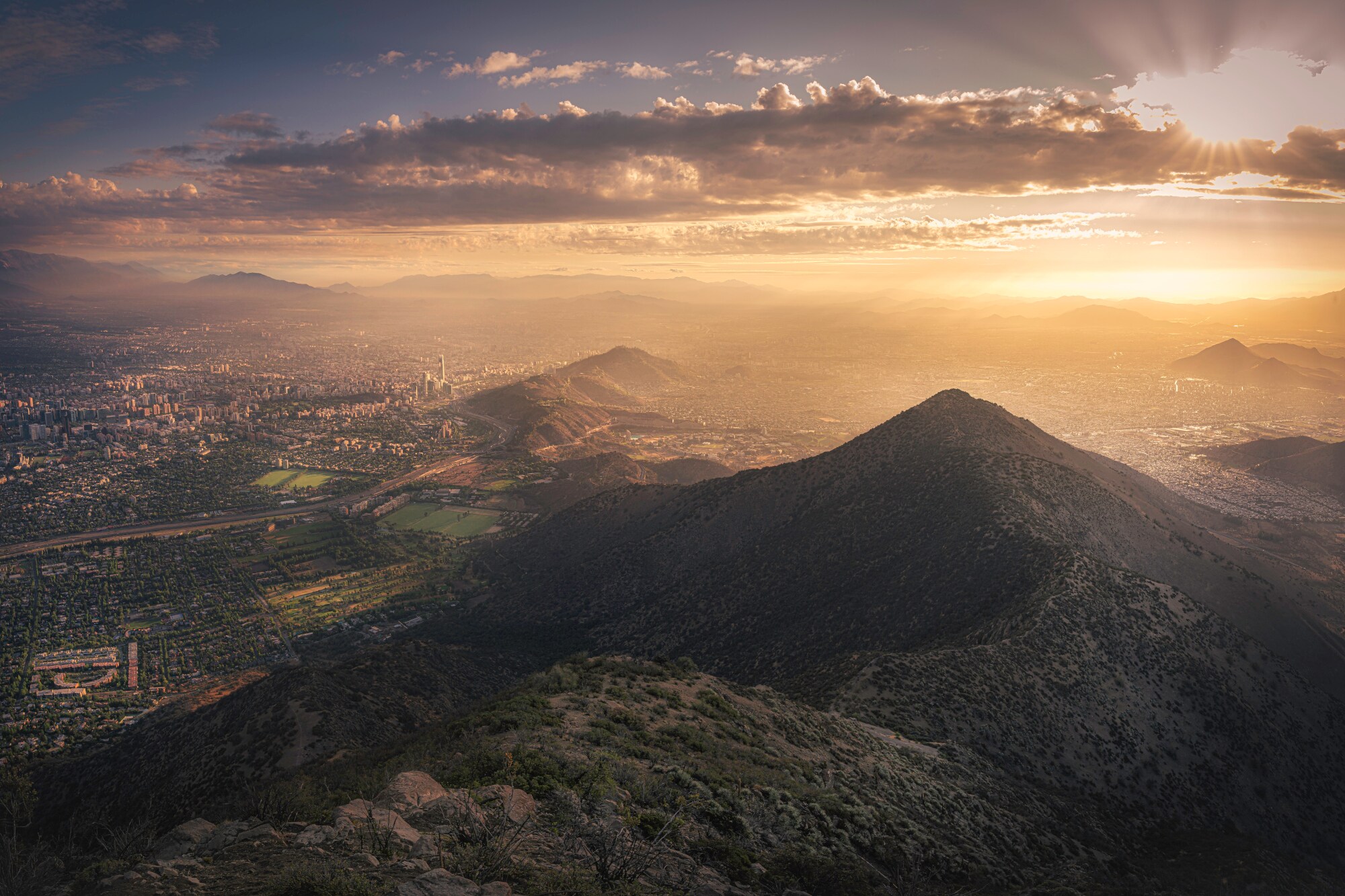 Luftbild von Santiago de Chile mit Sonne hinter Wolken