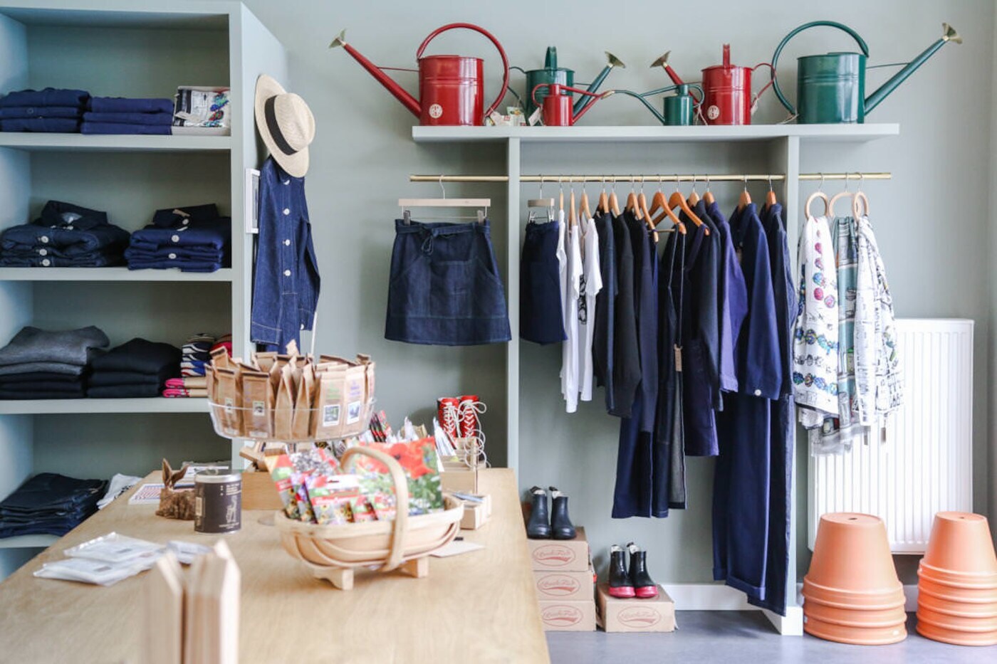 Ein Laden von innen, der Kleidung, Gießkannen und Blumentöpfe verkauft Ein Laden von innen, der Kleidung, Gießkannen und Blumentöpfe verkauft