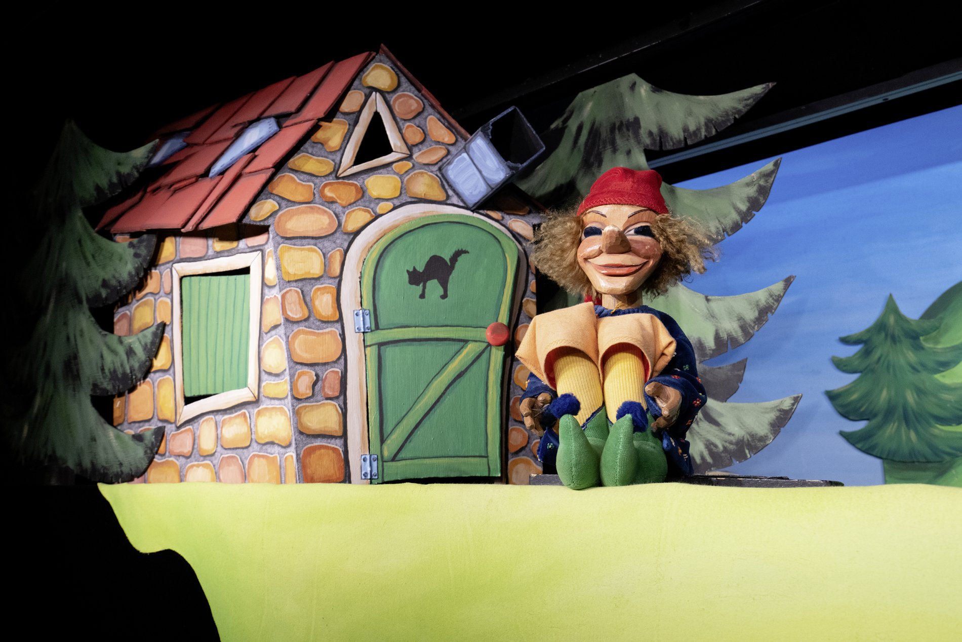 Eine Holzpuppe sitzt vor einer kleinen Papphütte