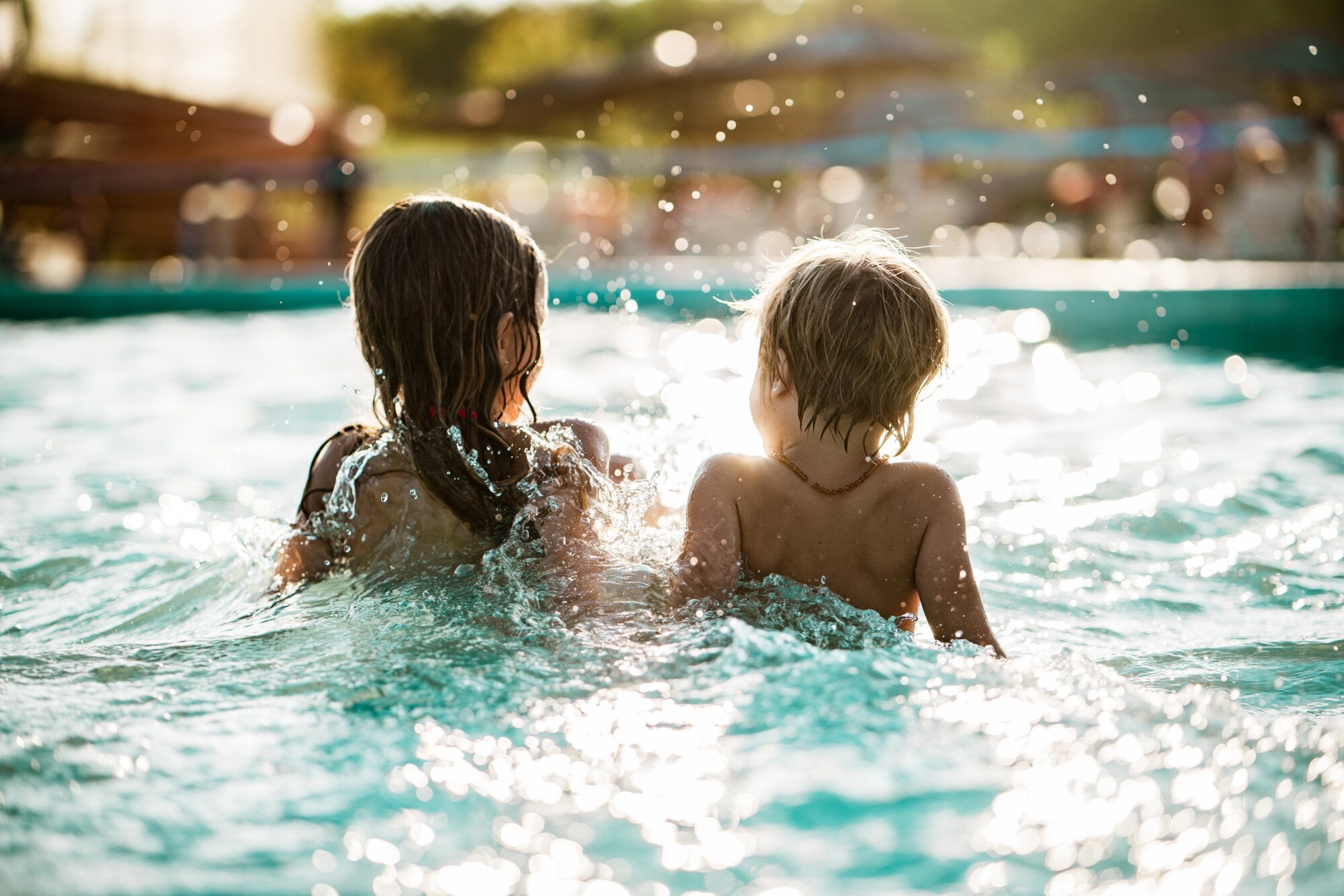 Zwei Kinder planschen im Schwimmbadbecken