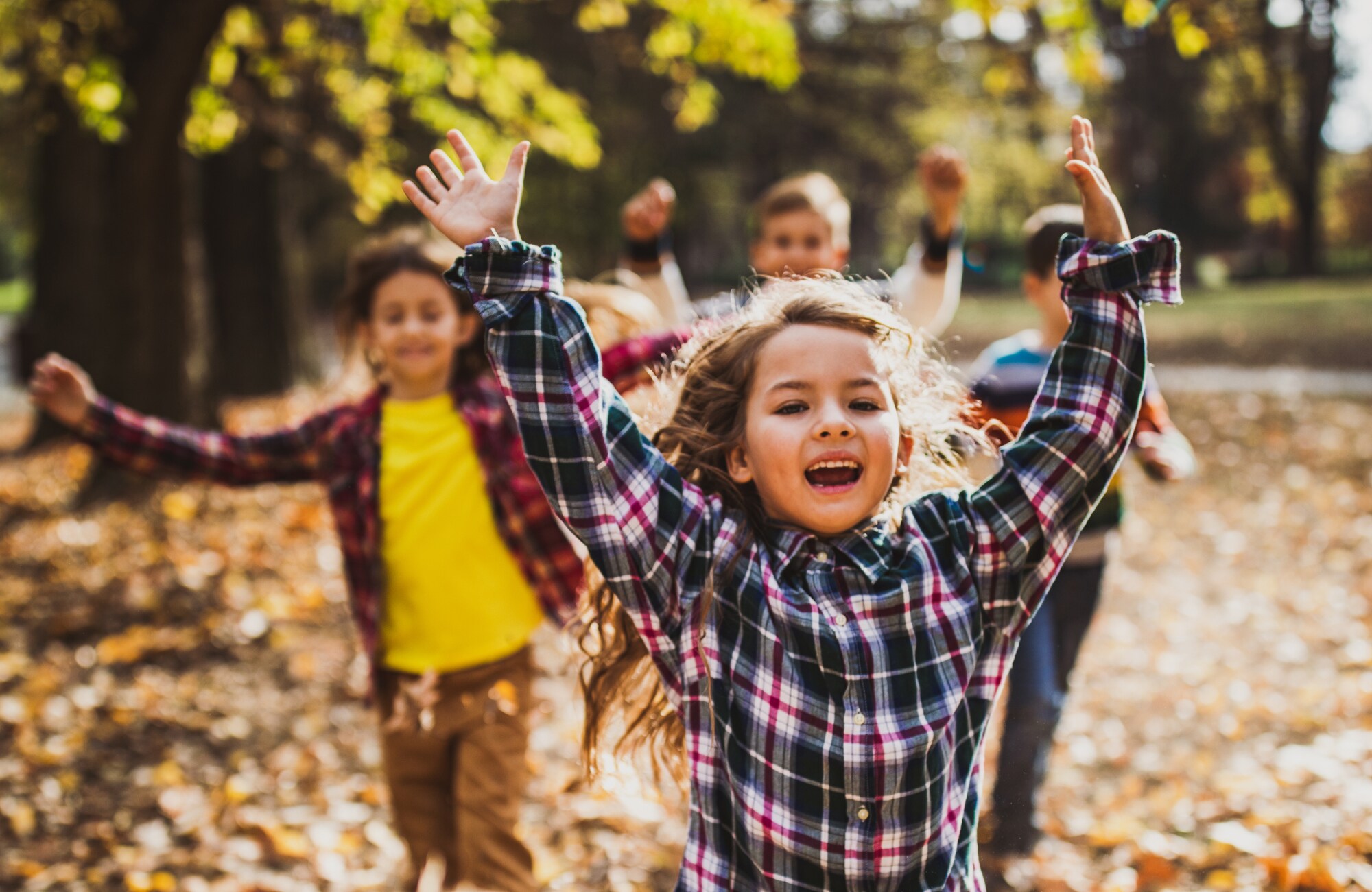 Vier fröhliche Kinder rennen im Freien durchs Laub Vier fröhliche Kinder rennen im Freien durchs Laub