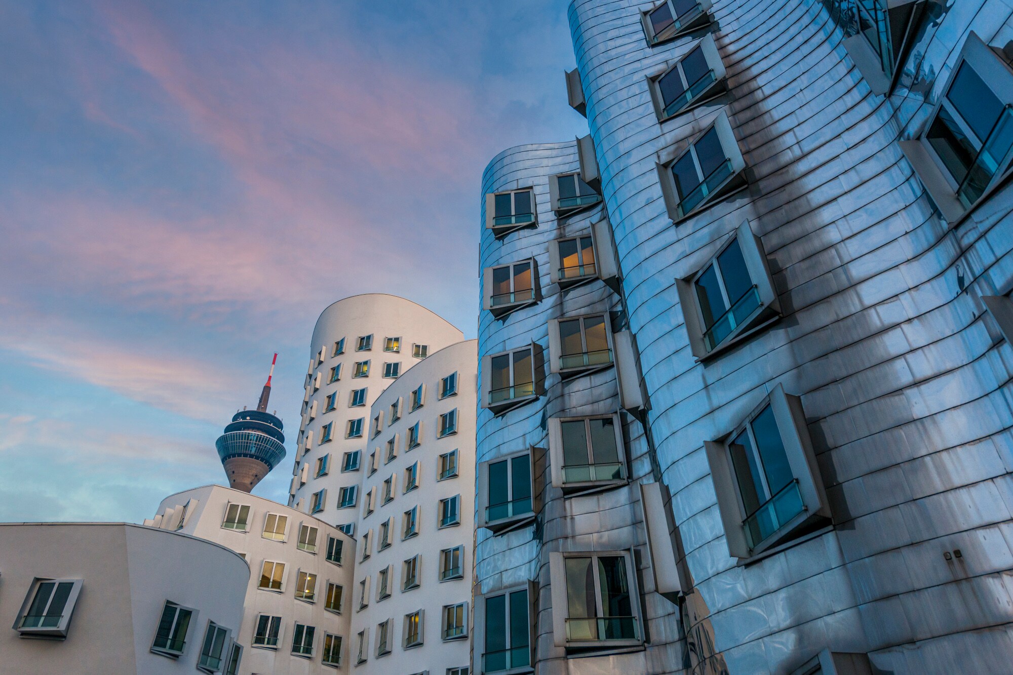 Geschwungene, moderne Gebäude in Düsseldorf mit Fernsehturm im Hintergrund