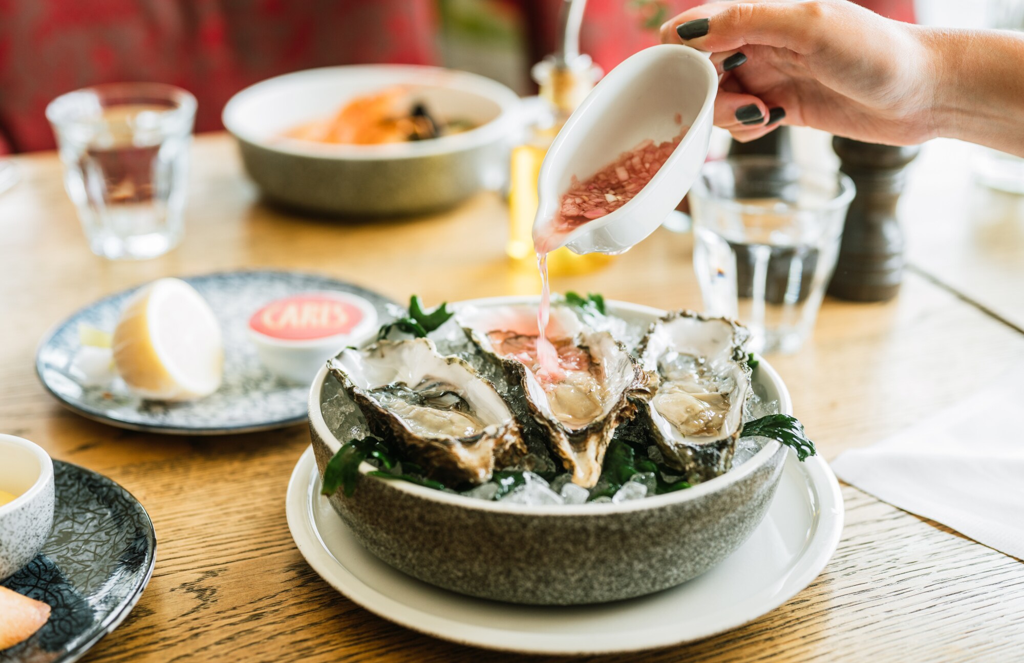 Drei Austern werden in einer Schale serviert und mit einem Dressing übergossen