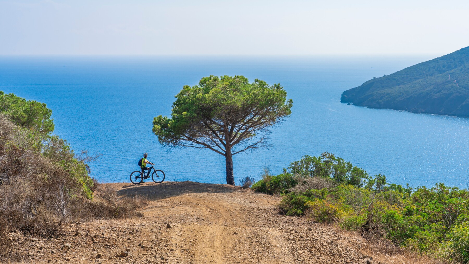 Ein Fahrradfahrer, der an einer Klippe die Aussicht auf das Meer genießt