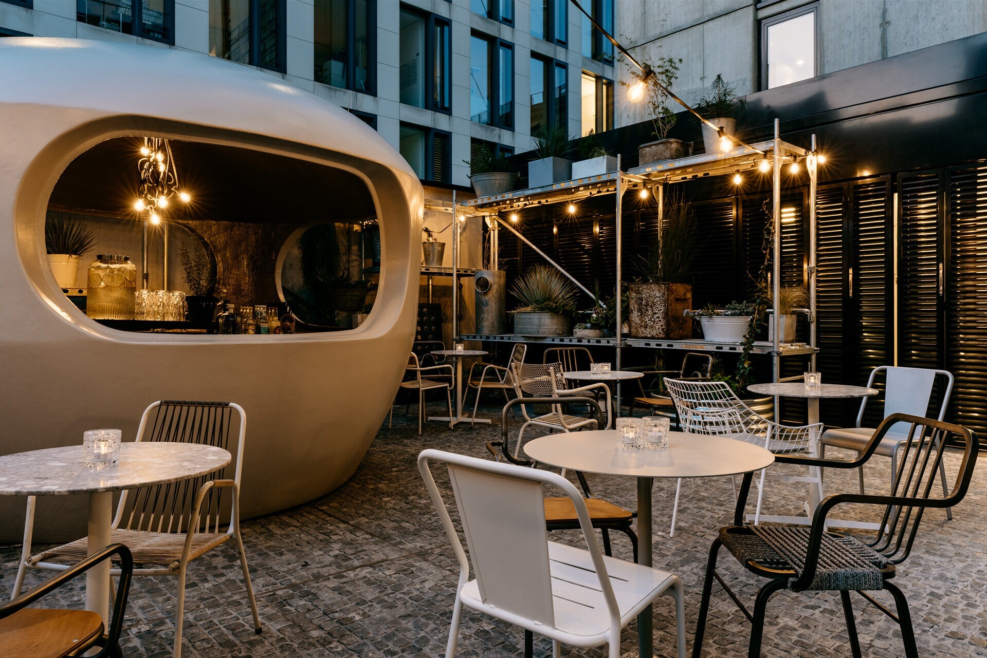 Innenhof mit Stühlen und einem Ufo-artigen Häuschen, aus dem Getränke serviert werden