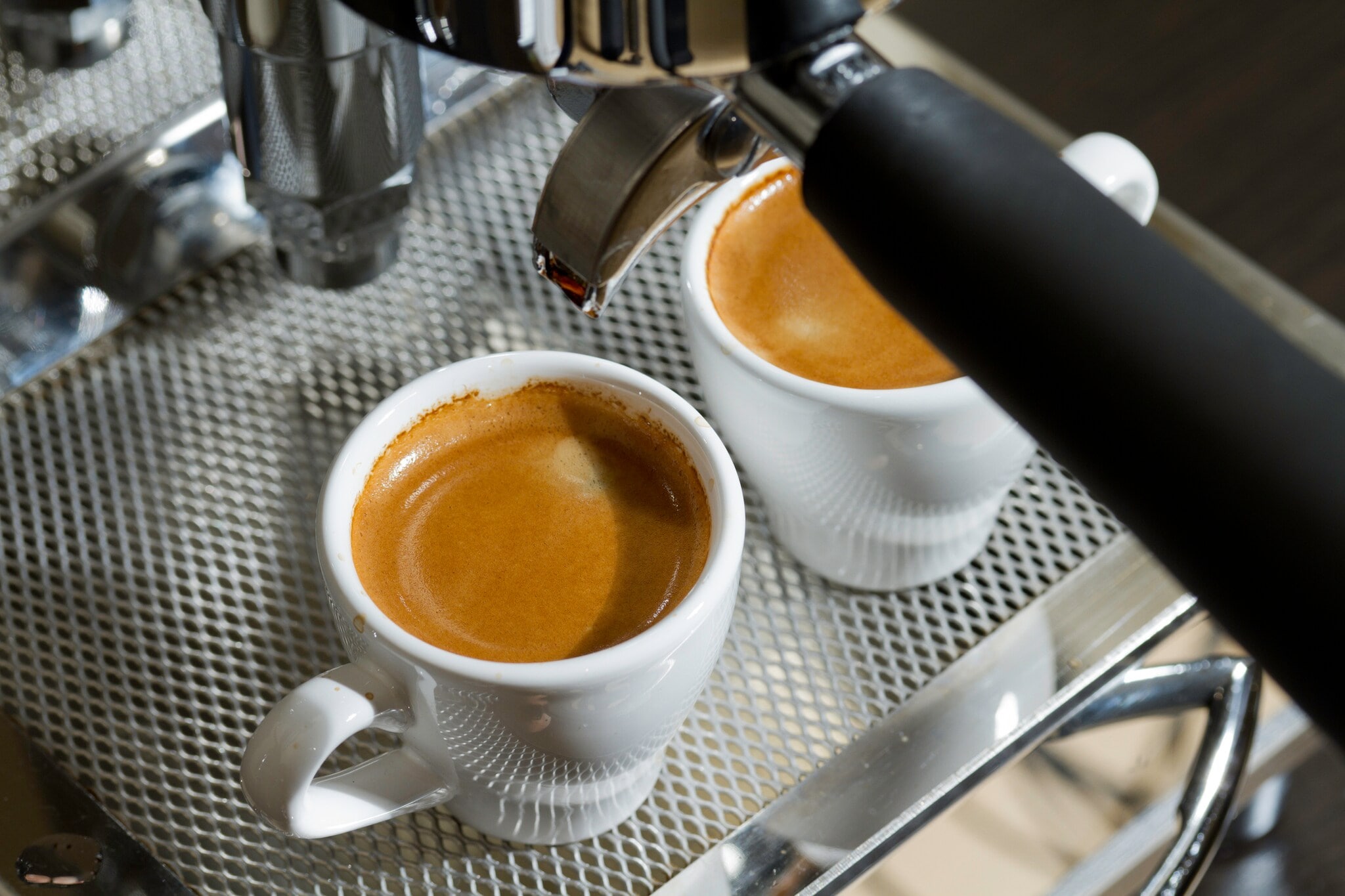 Zwei gefüllte Espressotassen, die aus einer professionellen Espressomaschine befüllt wurden Zwei gefüllte Espressotassen, die aus einer professionellen Espressomaschine befüllt wurden