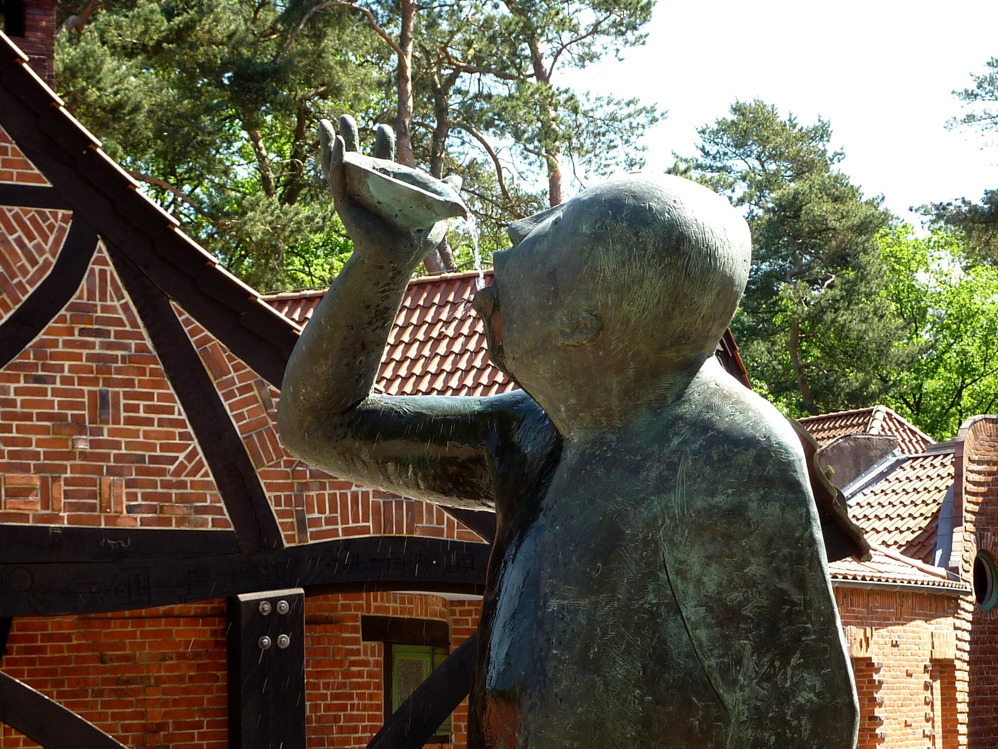 Fokus auf Brunnenelement, bei dem Wasser aus einer Schale in den Mund eines Mannes fließt Fokus auf Brunnenelement, bei dem Wasser aus einer Schale in den Mund eines Mannes fließt