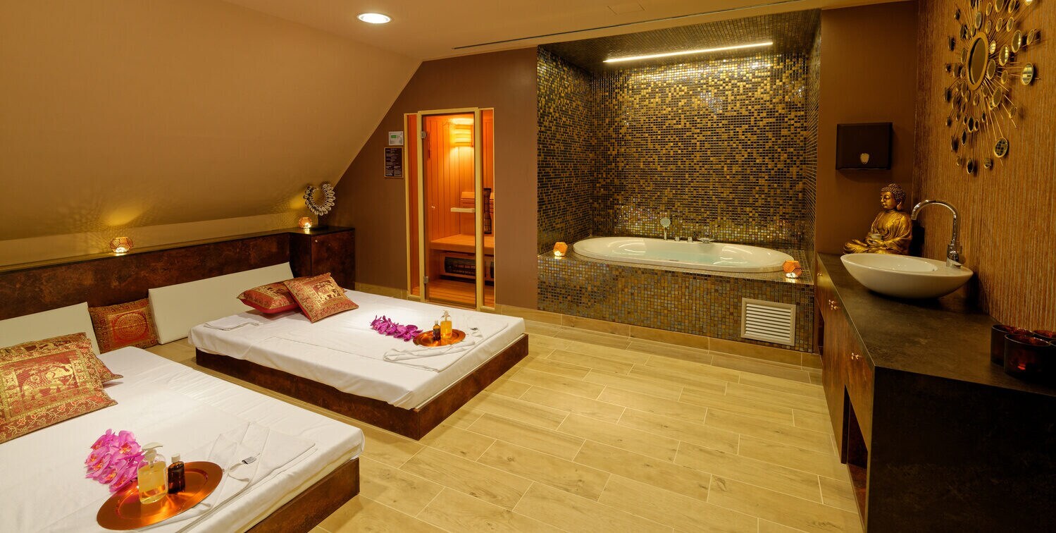 Wellnessbereich mit Badewanne, Betten und goldenen Dekoelementen