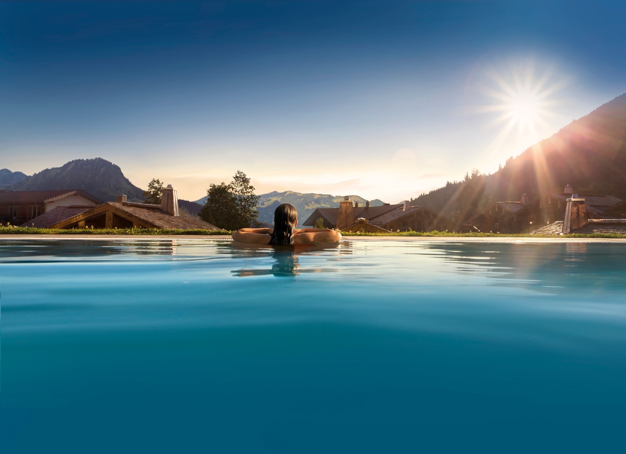 Rückansicht einer Person in einem Pool, im Hintergrund Berge Rückansicht einer Person in einem Pool, im Hintergrund Berge