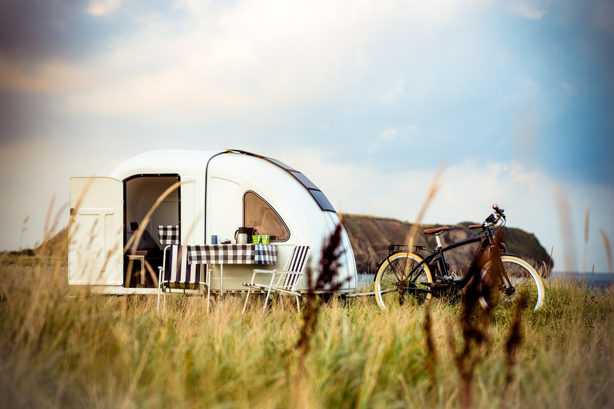 Ein Fahrrad mitten in der Natur mit einem Miniwohnwagen dahinter
