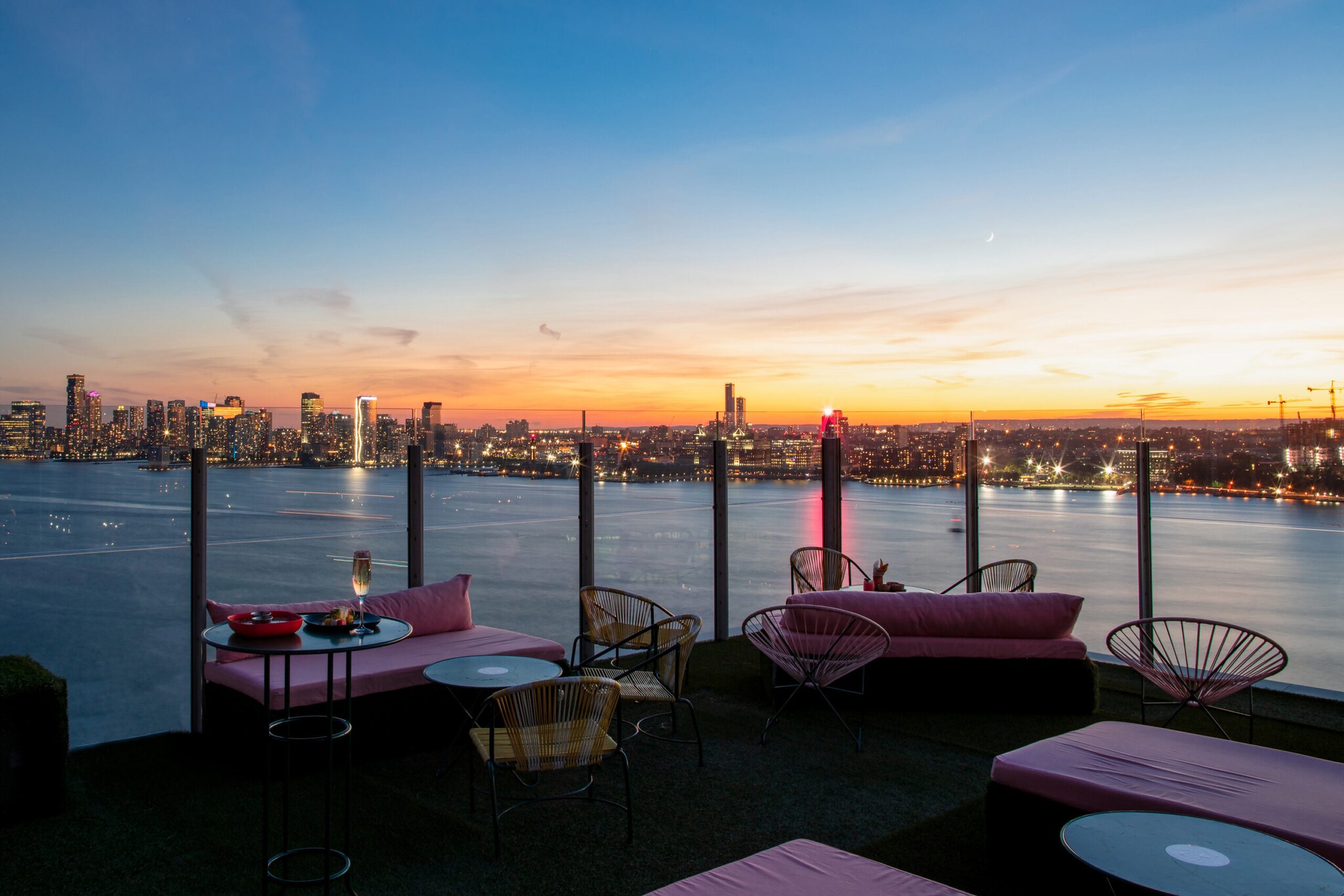 Eine Terrasse mit Polstermöbeln vor der Skyline New Yorks bei Sonnenuntergang