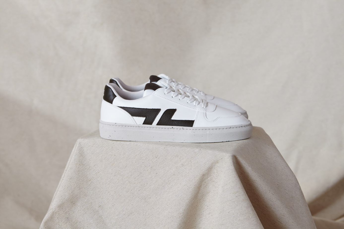 Weißer Sneaker mit schwarzen Applikationen von der Seite