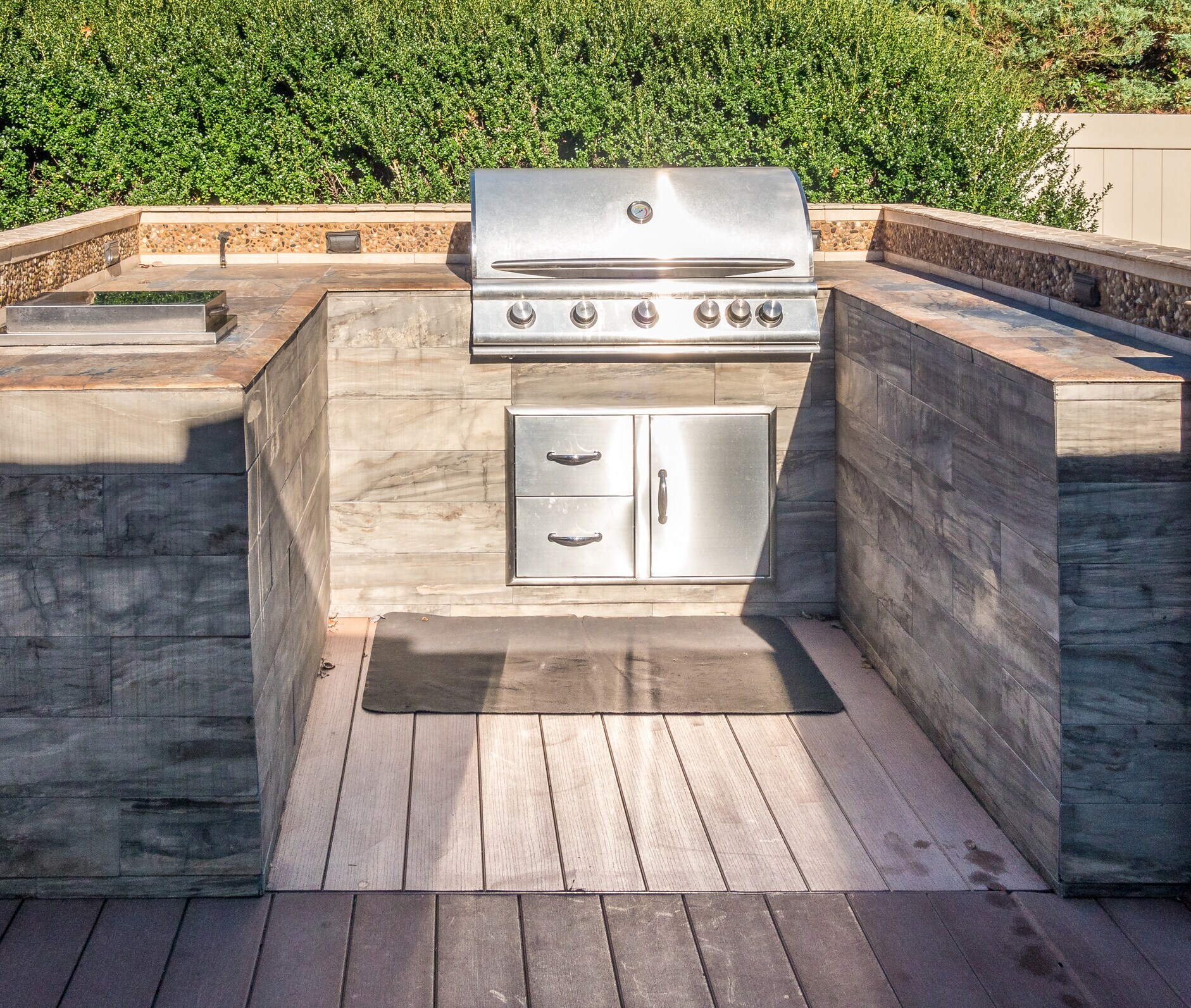 Eine Outdoorküche in Holzoptik mit einem integrierten Gasgrill. Eine Outdoorküche in Holzoptik mit einem integrierten Gasgrill.