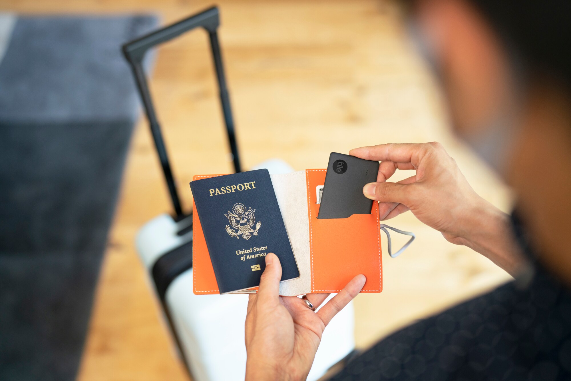 Eine Person hält einen Reisepass und einen Schlüsselfinder in der Hand