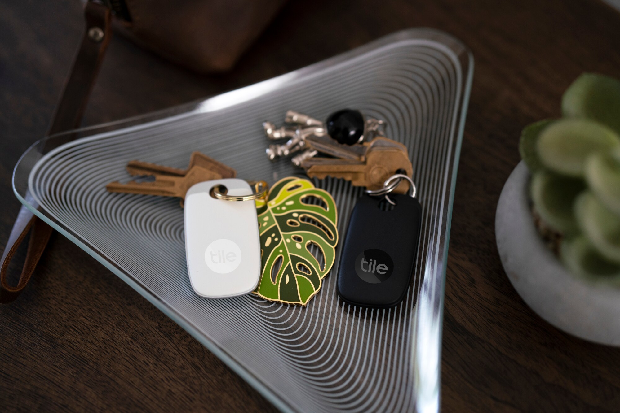 Zwei Schlüsselfinder der Marke Tile an einem Schlüsselbund in einer Schale