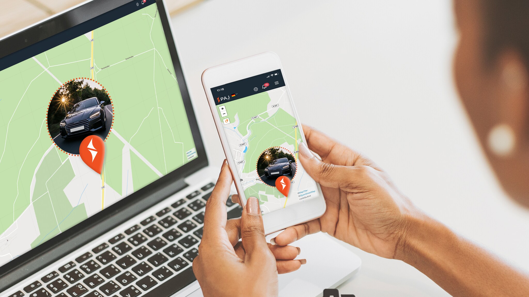 Eine Person hält ein Smartphone in der Hand und sitzt dabei vor einem Laptop Eine Person hält ein Smartphone in der Hand und sitzt dabei vor einem Laptop
